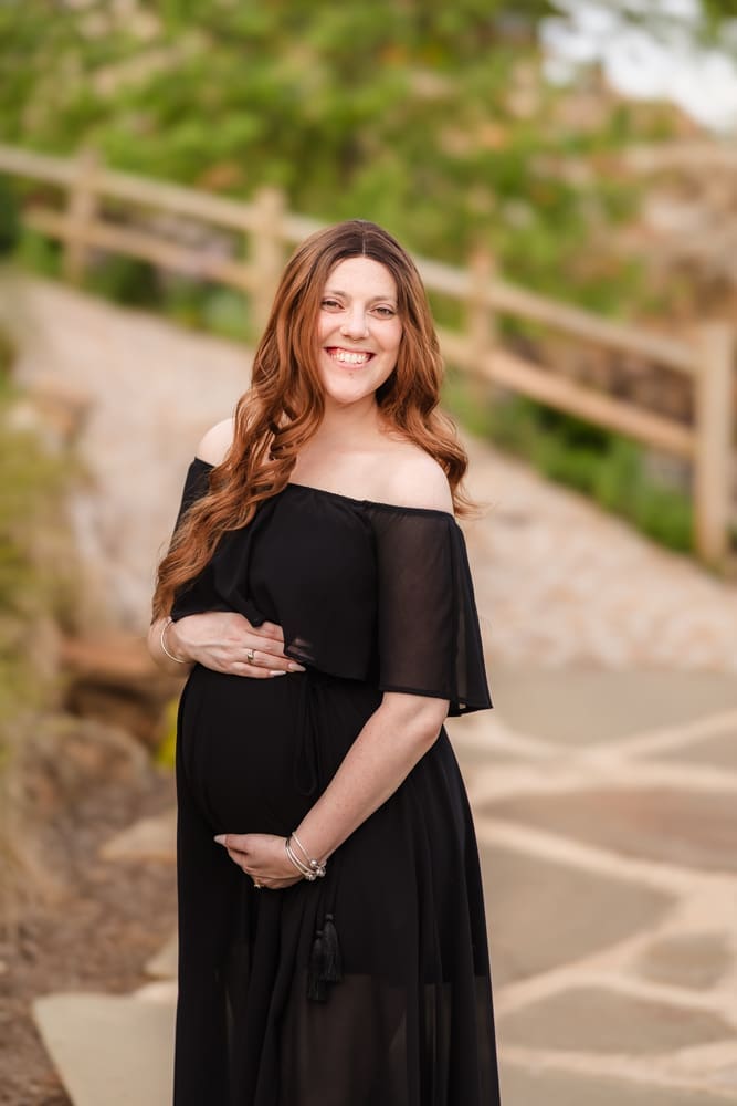 mom standing on path smiling during fantasy inspired knoxville maternity photography session at ancient lore village