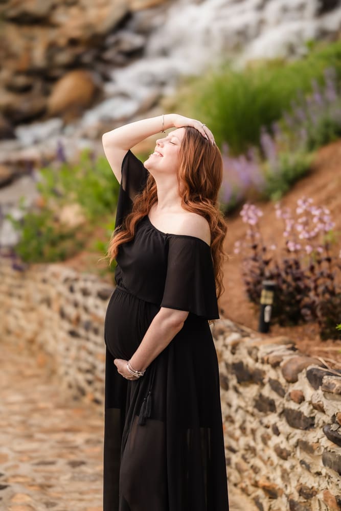mom soaking up the sun in front of waterfall during fantasy inspired knoxville maternity photography session at ancient lore village