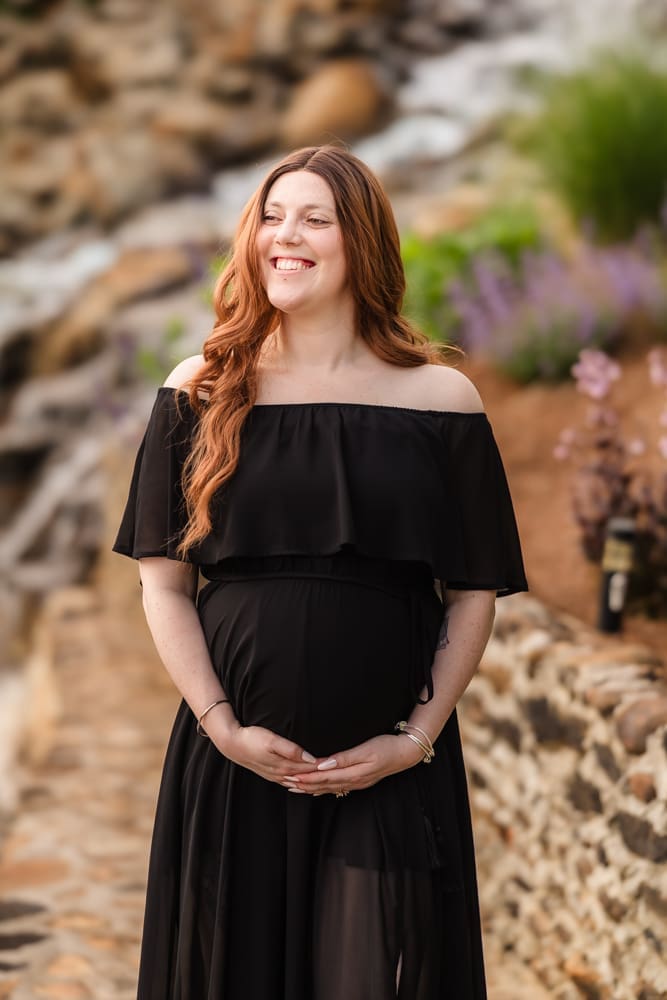 mom standing in front of waterfall during fantasy inspired knoxville maternity photography session at ancient lore village