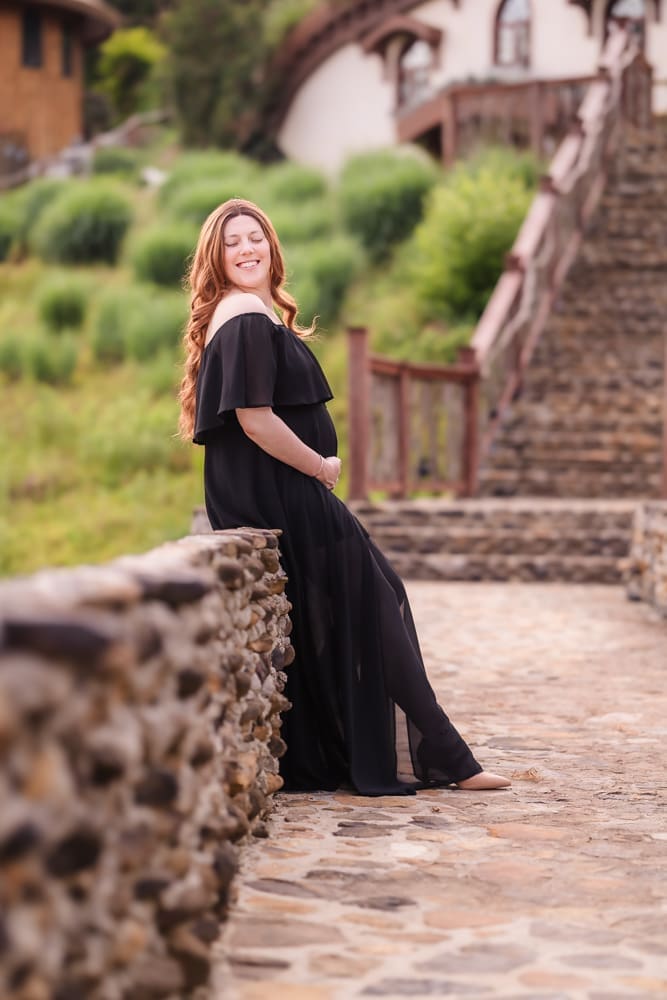 mom sitting on stonework during fantasy inspired knoxville maternity photography session at ancient lore village