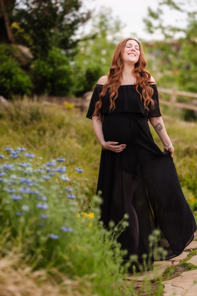 mom playing with dress in field during fantasy inspired knoxville maternity photography session at ancient lore village