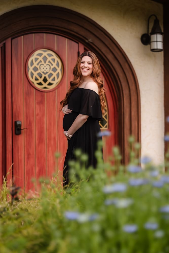 mom standing in front of hobbit hole during fantasy inspired knoxville maternity photography session at ancient lore village
