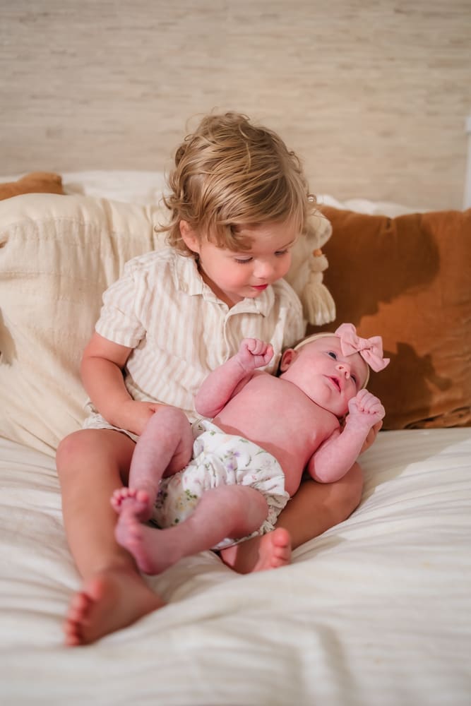 Toddler brother holding his newborn baby sister during a Powell TN newborn session