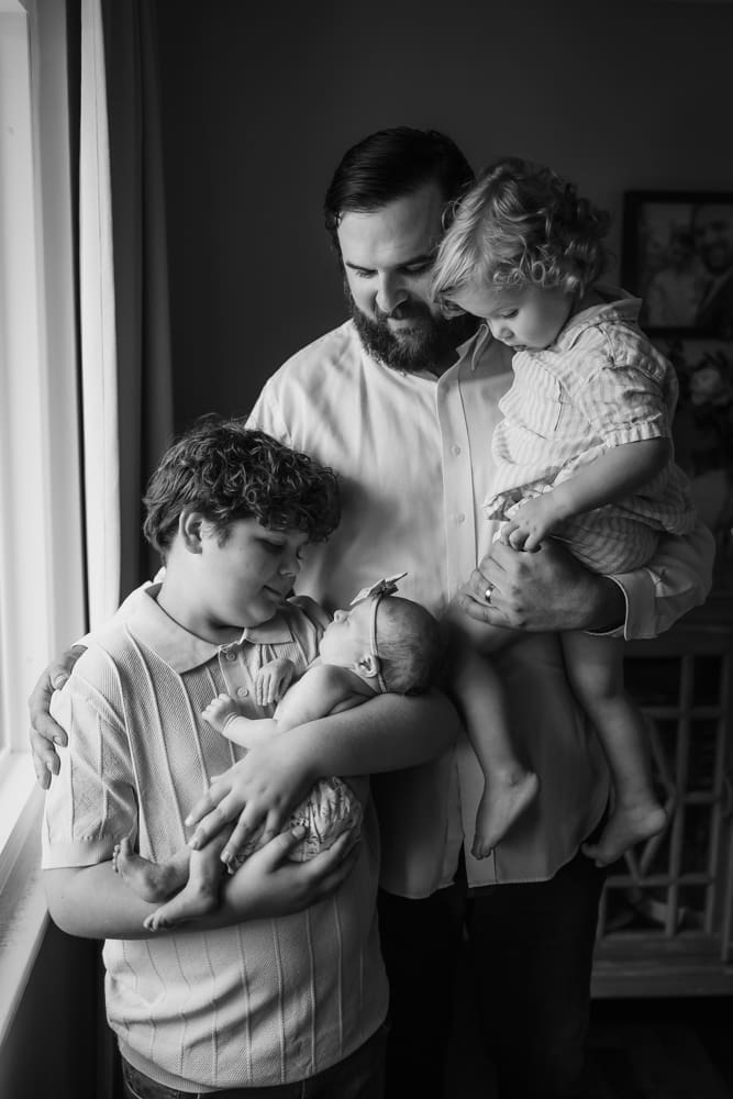 Black and white family portrait of father and sons with newborn baby during an in-home session in Powell TN
