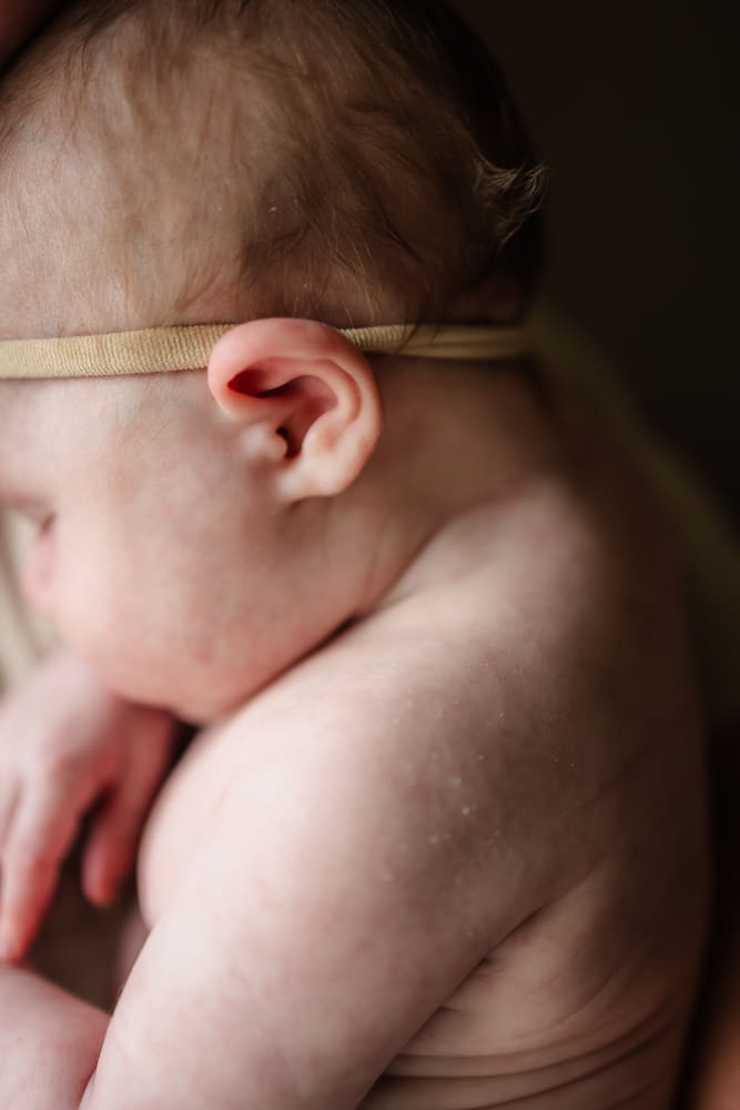 Newborn baby resting against a family member during in-home newborn photography in Powell TN