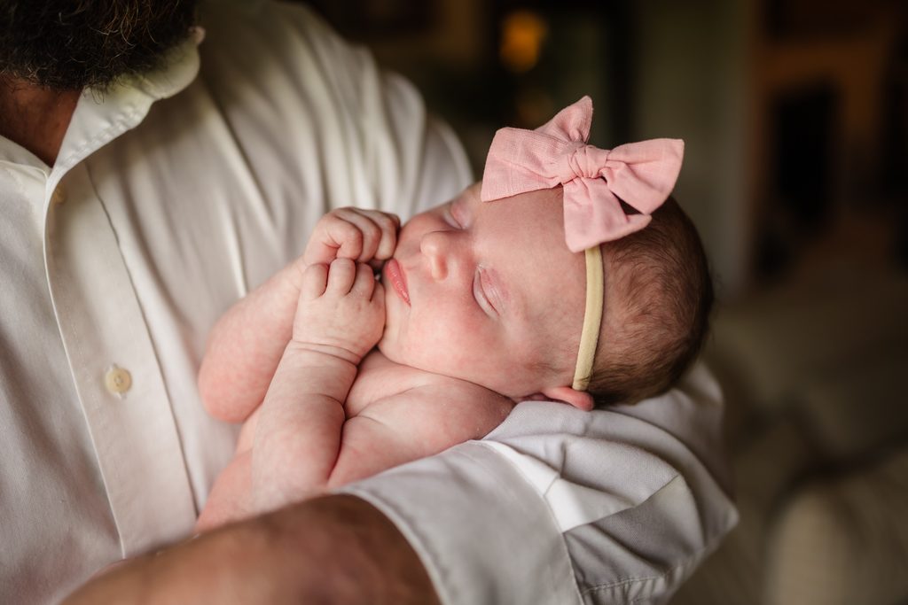 Newborn baby girl resting in her father's arms during lifestyle newborn photography in Powell TN