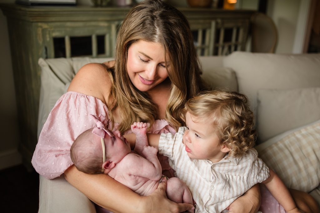 Mother cuddling her newborn baby and toddler during an in-home newborn session in Powell TN
