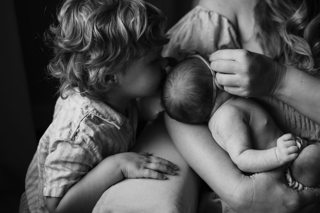 Black and white sibling moment with newborn baby during lifestyle newborn photography in Powell TN