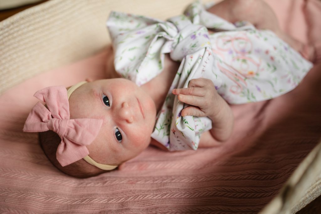 Newborn baby girl awake in a Moses basket during lifestyle newborn photography in Powell TN